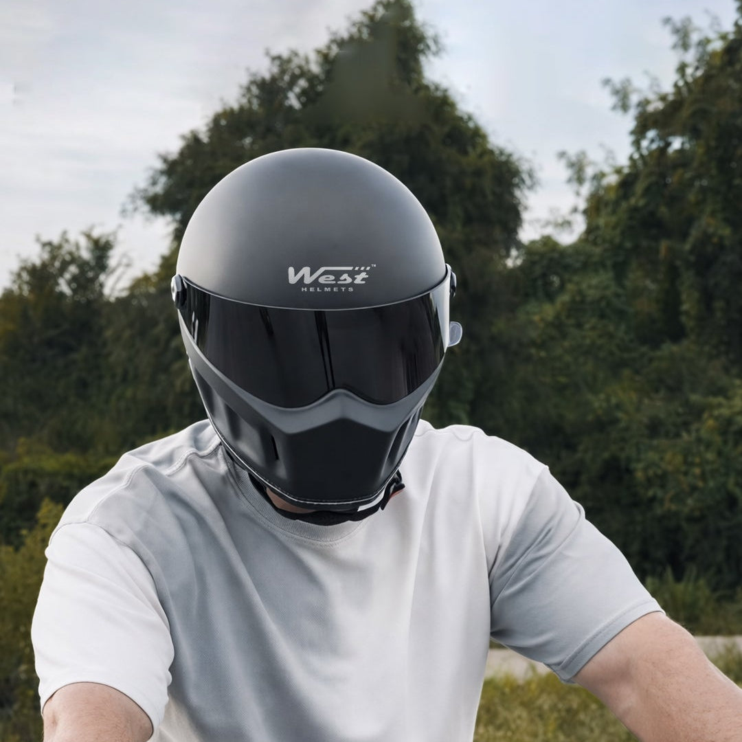 Person wearing a black helmet with 'West' branding on a motorcycle.
